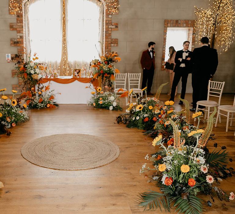 Autumnal orange and yellow wedding flowers with rug wedding ceremony decor at Gracehall in Northern Ireland