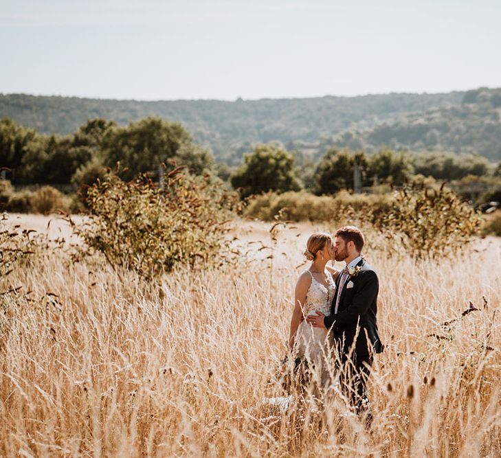 Bride & groom kiss in golden fields for couples portraits 