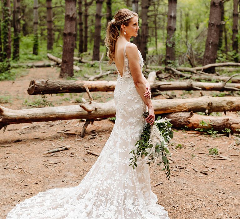 Bride poses in the woodlands with an open back 