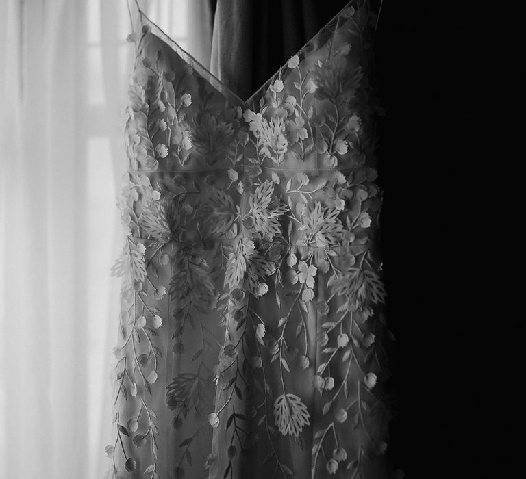 The bride's flower applique wedding dress is hung up ready for the bride 