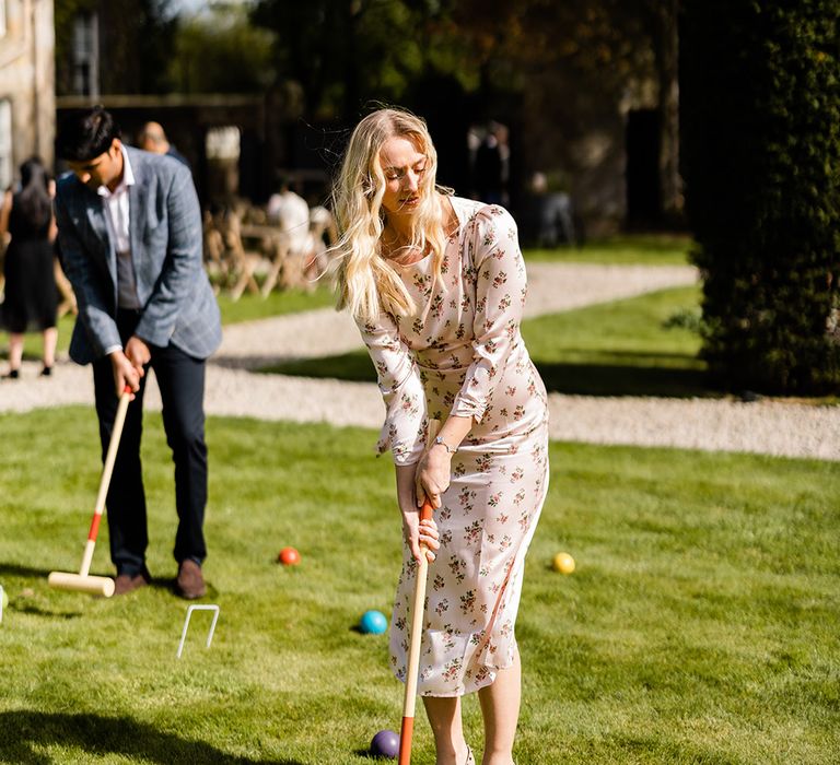 Wedding guests play crocket on the lawn outdoors 