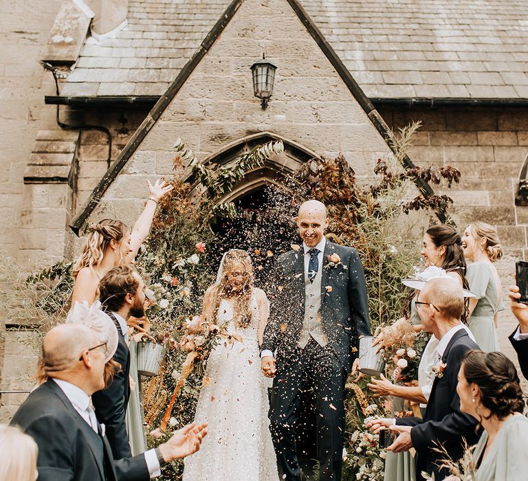 Fun confetti exit photo of the bride and groom exiting the church after their ceremony for rustic luxe wedding 