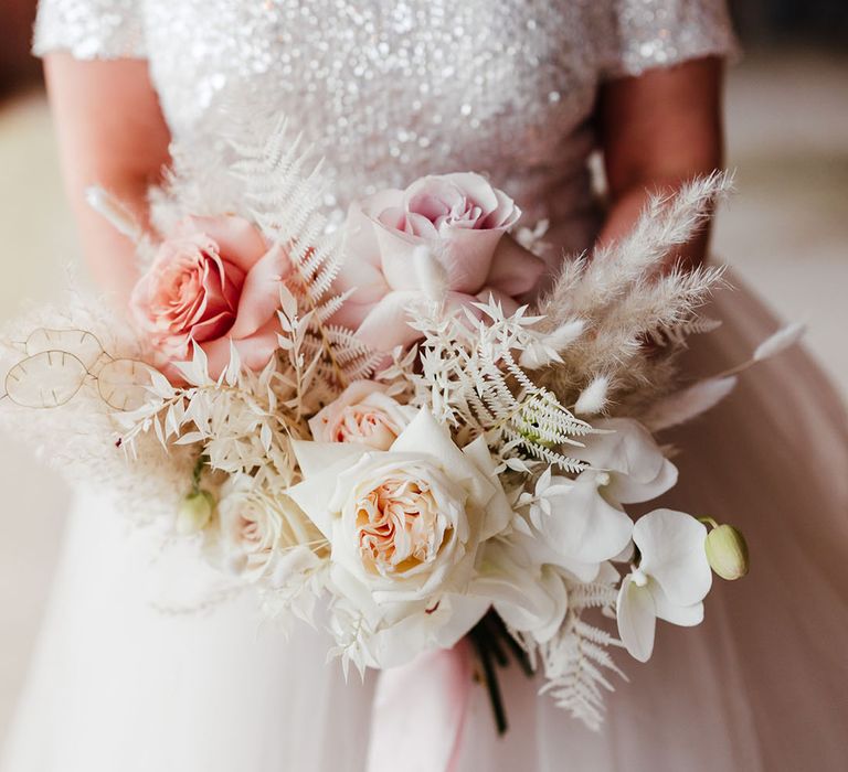 Pink rose and white orchid with dried grass making up the bridal bouquet for the winter Christmas wedding 