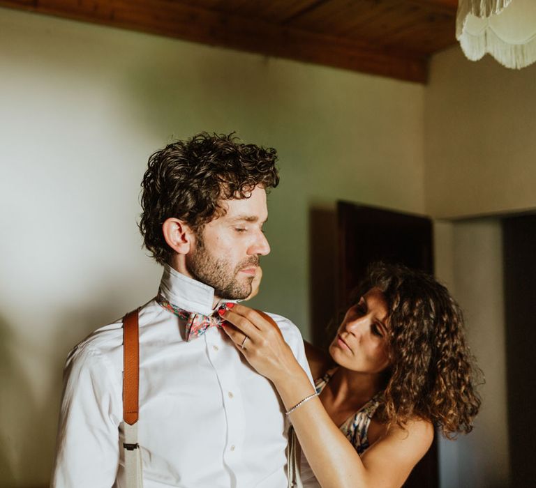 Groom getting ready wearing a white shirt with burnt orange braces