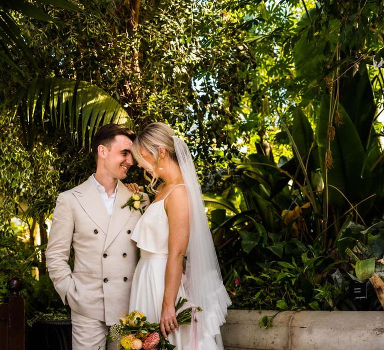 Summer wedding with citrus colour scheme with the bride in satin pyjamas with ruffle veil with the groom in cream suit 