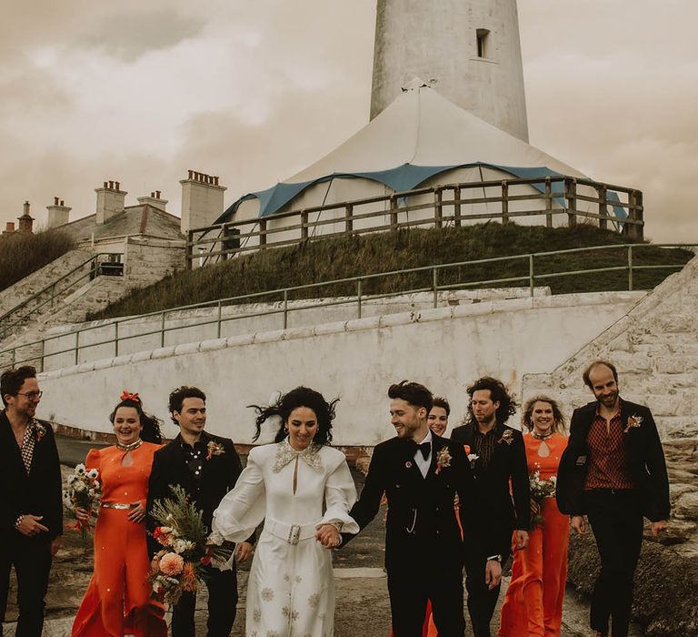 Retro 70s inspired lighthouse wedding with wedding party in pops of autumnal orange shades 