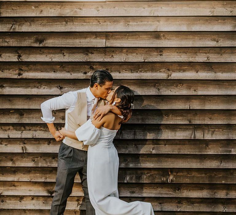 groom in a beige horseshoe waistcoat kissing his bride at The Canary Shed 