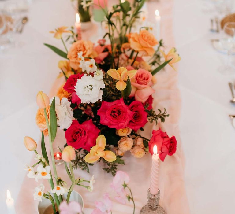 Wedding table centrepieces with pink and orange garden roses, orange floribunda, yellow ranunculus flowers, foliage and Iceland poppies 