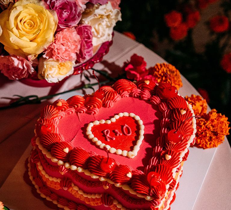 Heart shaped bright red and orange retro wedding cake with maraschino cherries on top 