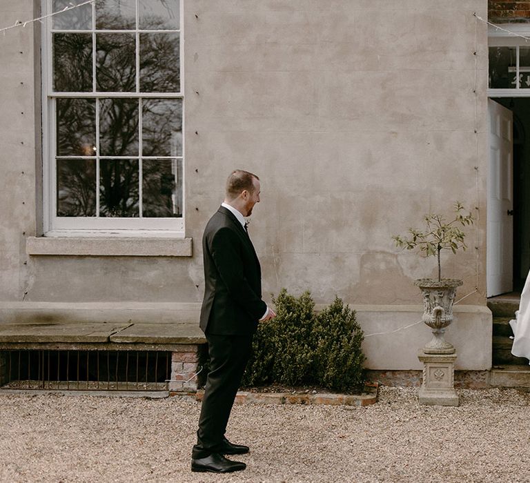 Bride in an off the shoulder wedding dress walking out to see the groom for their cute first look moment 