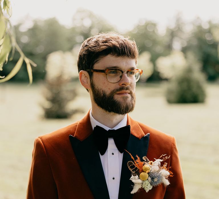 Groom in orange velvet tuxedo with epic dried flower buttonhole 