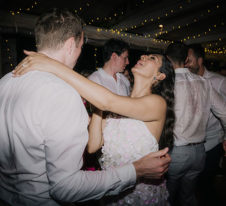 Bride in short sequin wedding reception dress dances with groom in white shirt at Restaurant park Hvar wedding reception