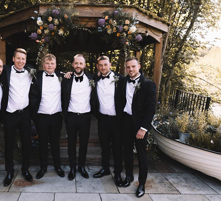 Groomsmen in black tuxedos for outdoor wedding 