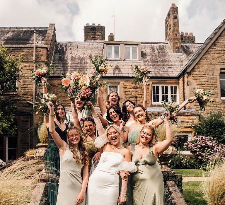 Bridal party group wedding photo with the bridesmaids wearing mismatched green bridesmaid dresses 