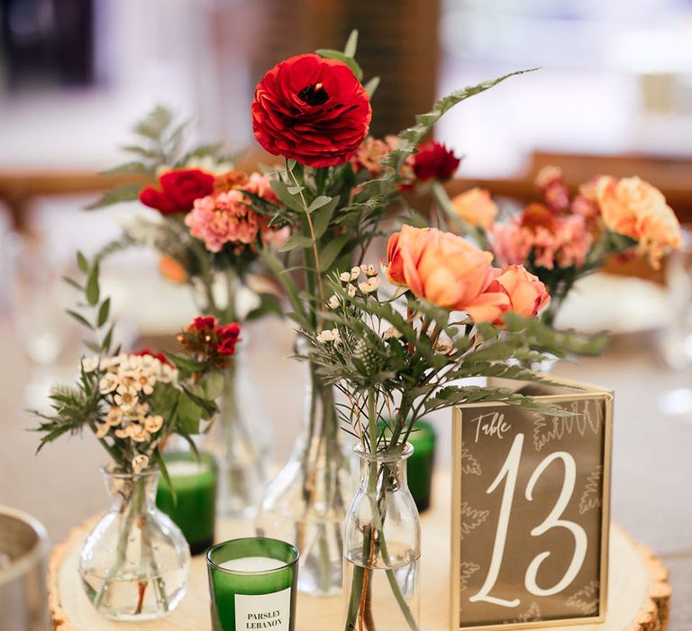 Wood slice table decoration centrepiece idea with bud vases full of festive red wedding flowers 