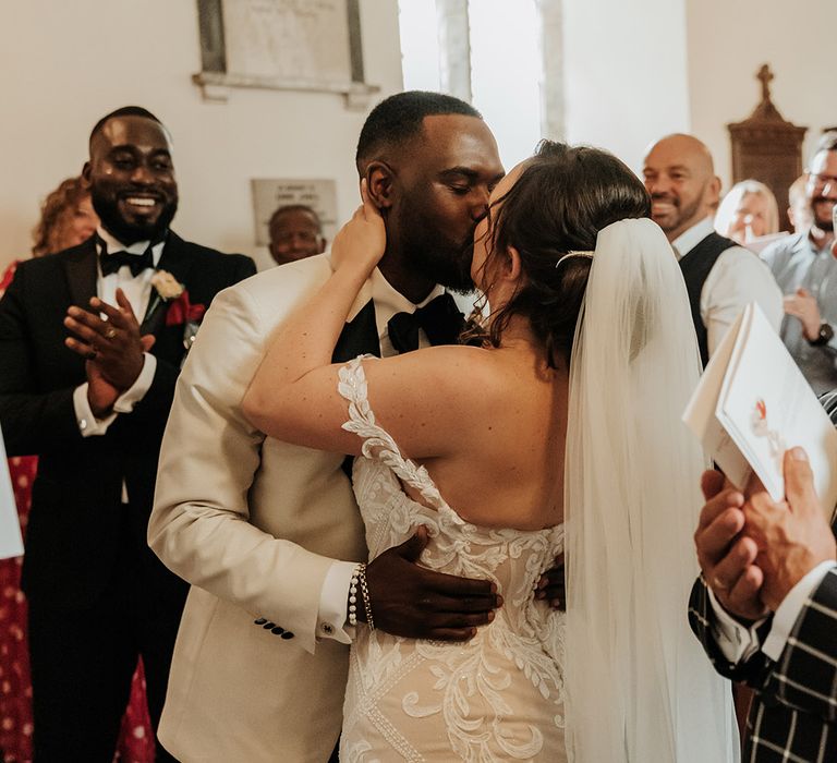 Bride and groom share their first kiss together at their church ceremony 