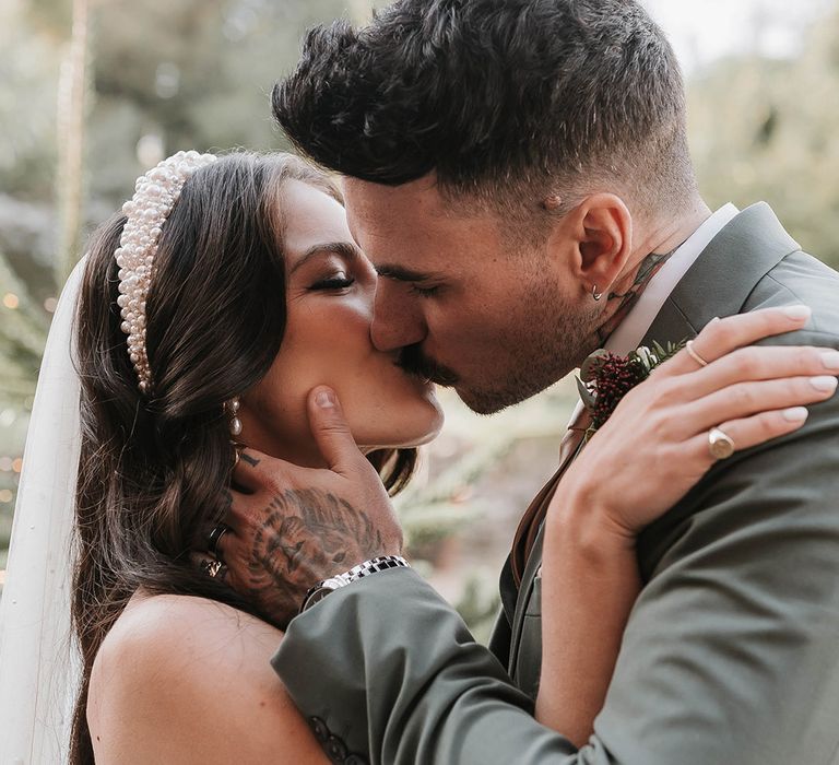 The bride and groom share their first kiss as a married couple after their outdoor wedding ceremony 