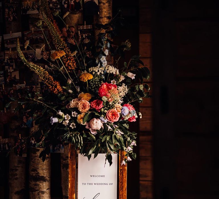 Wedding welcome sign at rustic barn wedding with colourful flower decorations 