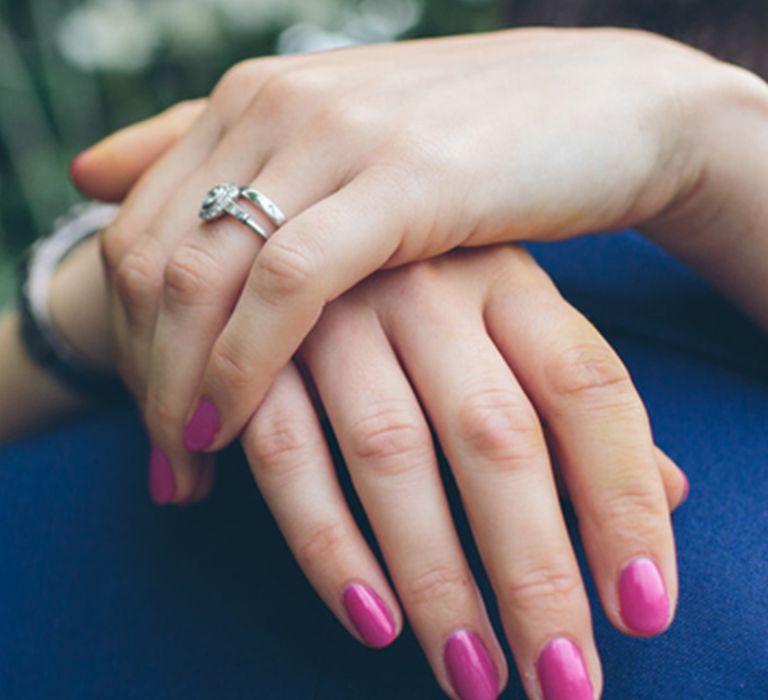 Bride embraces the groom with bright pink wedding nails 