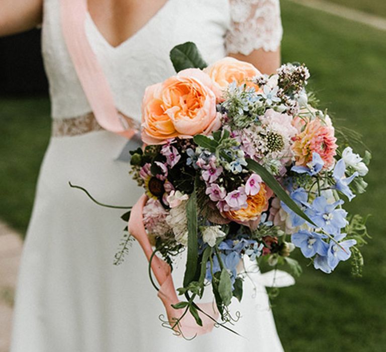 Bride carrying pink, orange and blue wedding bouquet for summer wedding 