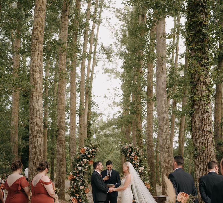 Outdoor wedding ceremony in Sicily with the bride and groom standing in front of a flower arch wedding altar decoration 