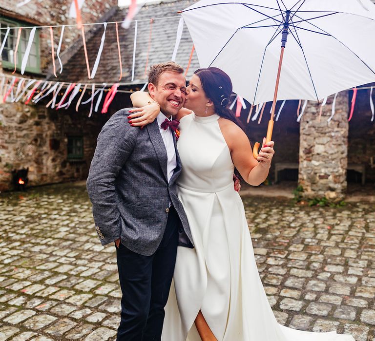 Rainy wedding day with couple posing with umbrella 