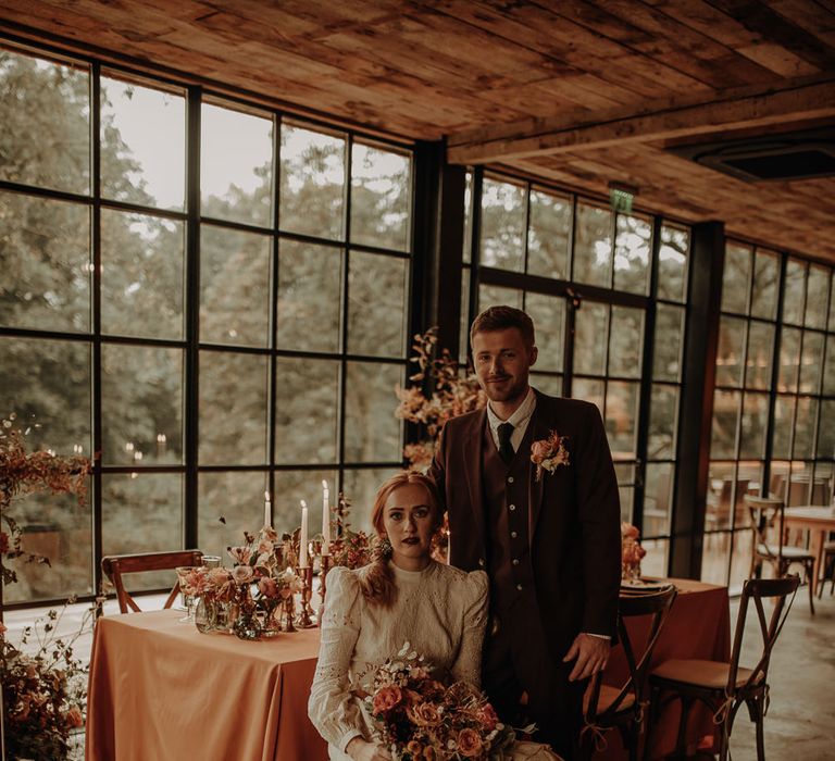 Bride and groom sitting at their intimate reception with the bride in a high neck wedding dress 