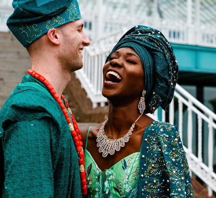 Bride and groom in green Nigerian outfits laughing together 