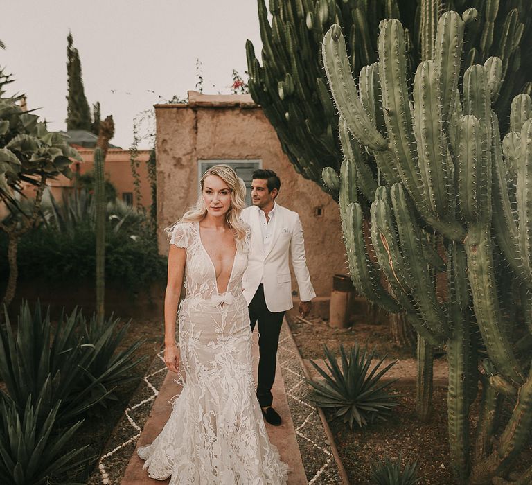 Portrait of a bride in an appliqué Berta bridal gown and a groom in white dinner jacket 