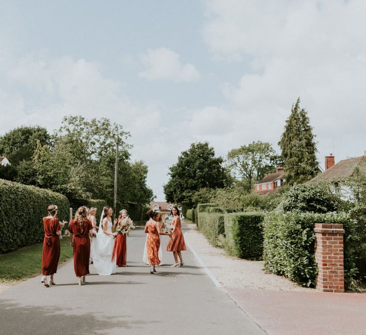 Bridal party in oranges dresses walking through the village 