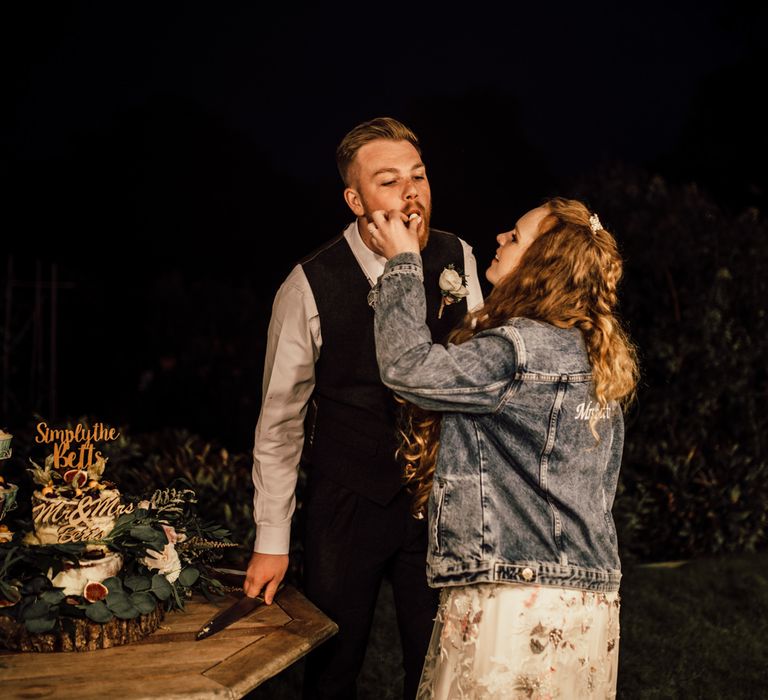 Bride & groom feed each other wedding cake 