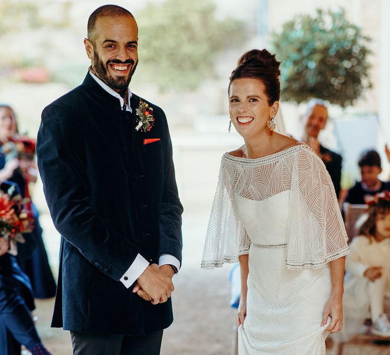 Bride & groom stand together during fairy lit ceremony