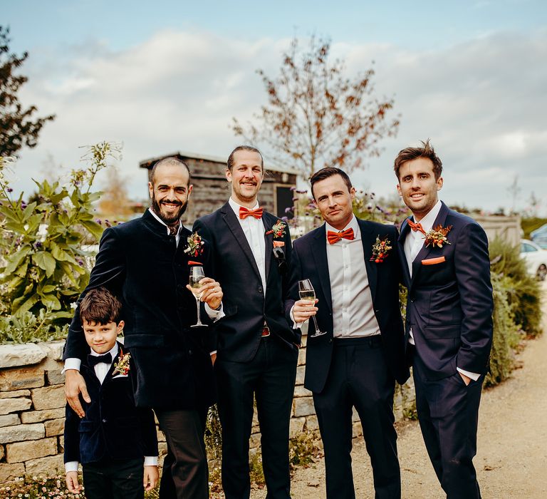 Groom stands with his groomsmen in deep blue suits