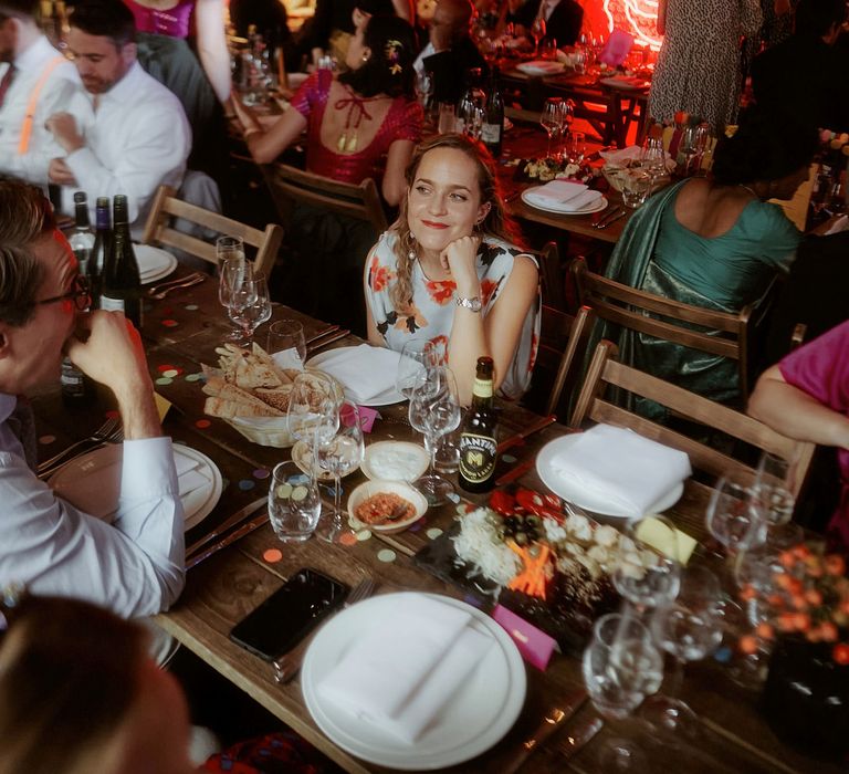 Wedding reception with colourful confetti on the tables and red rose neon sign 