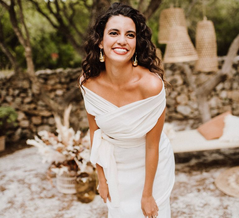 Bride laughs wearing golden statement earrings 