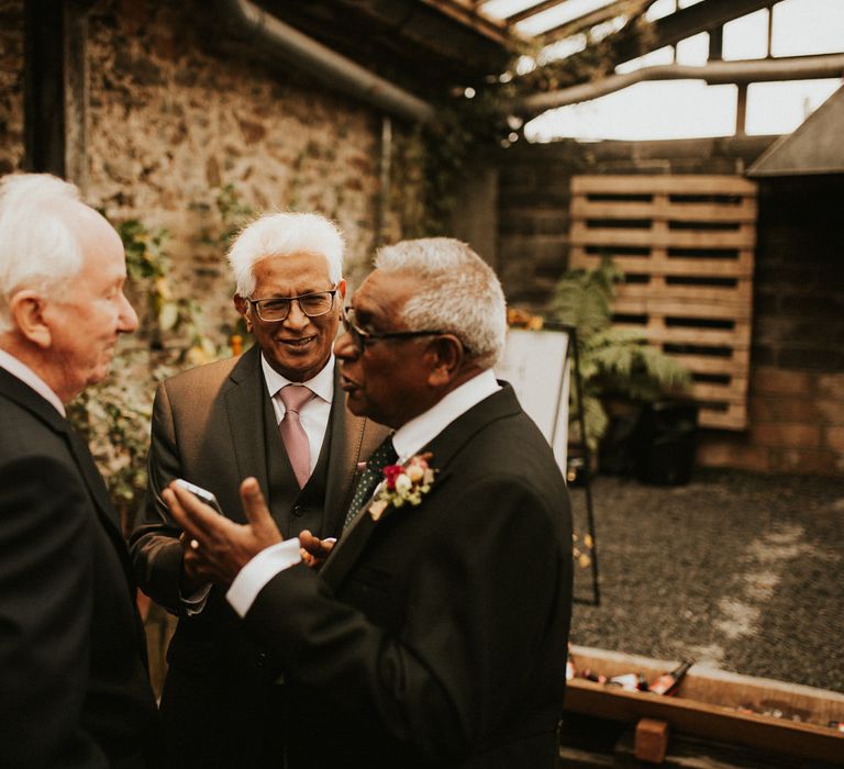 Wedding guests in dark suits talking at autumn themed wedding at Anran in Devon