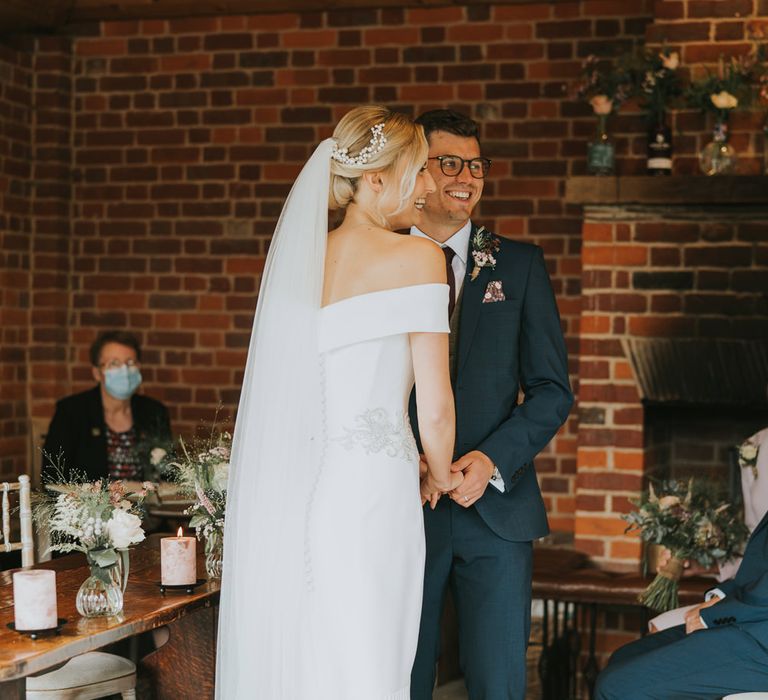 Bride wears fitted fishtail wedding gown with her groom during wedding ceremony