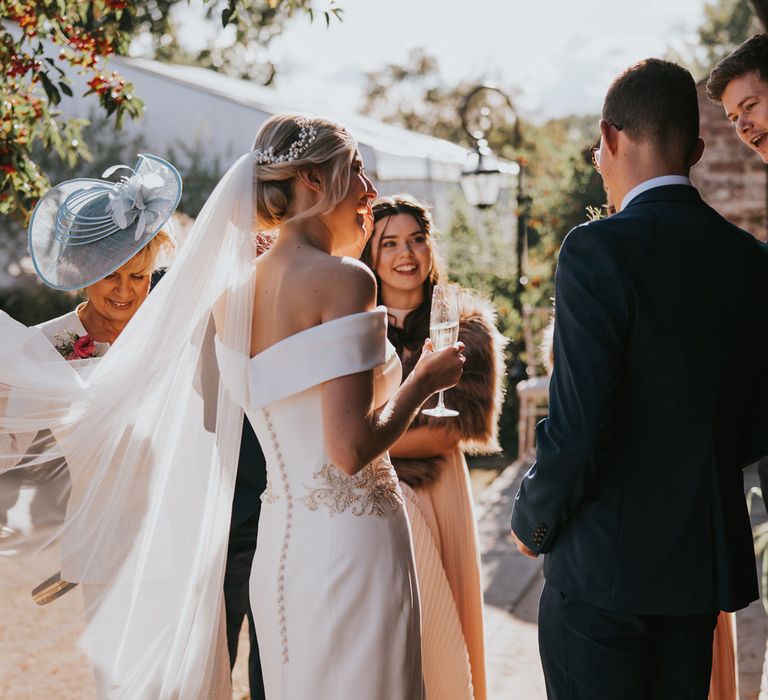 Bride laughs in fitted fishtail wedding dress with veil blowing in the wind