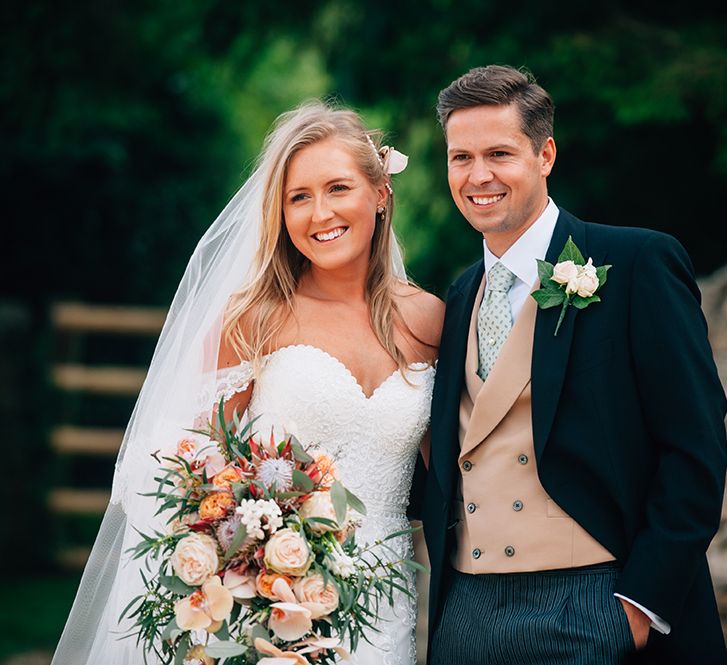 Bride and groom photography with peach wedding bouquet with orchids, roses and King Proteas