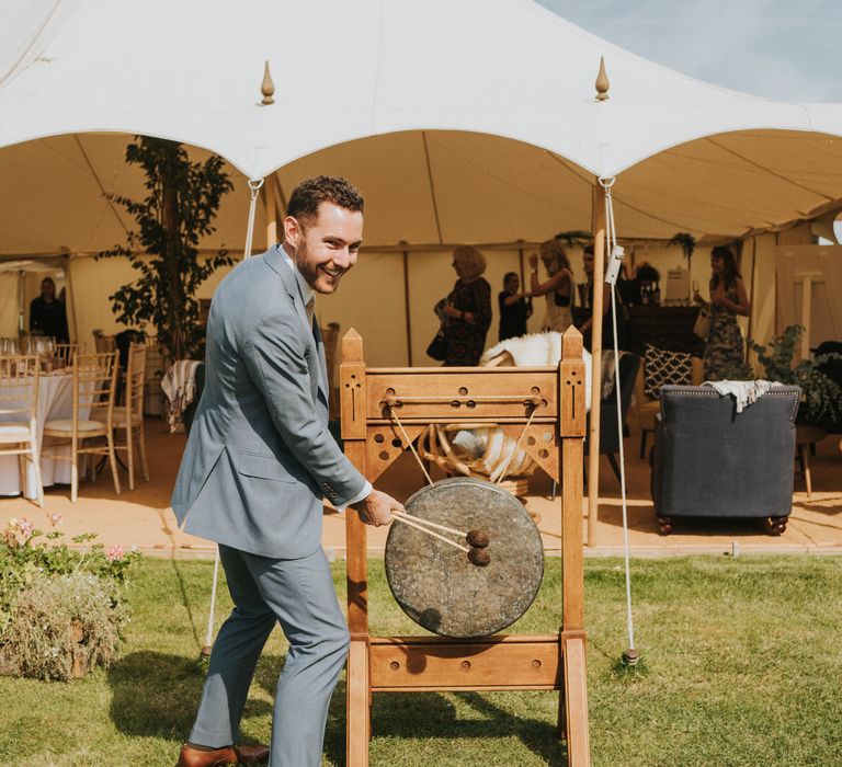 Banging the gong to usher guests into the marquee 