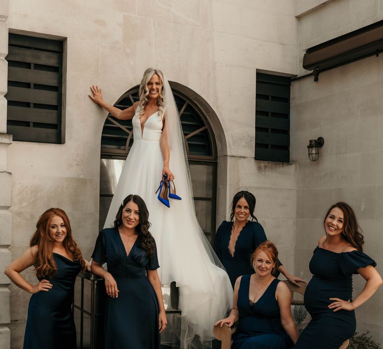 Bride poses with her bridesmaids in navy dresses