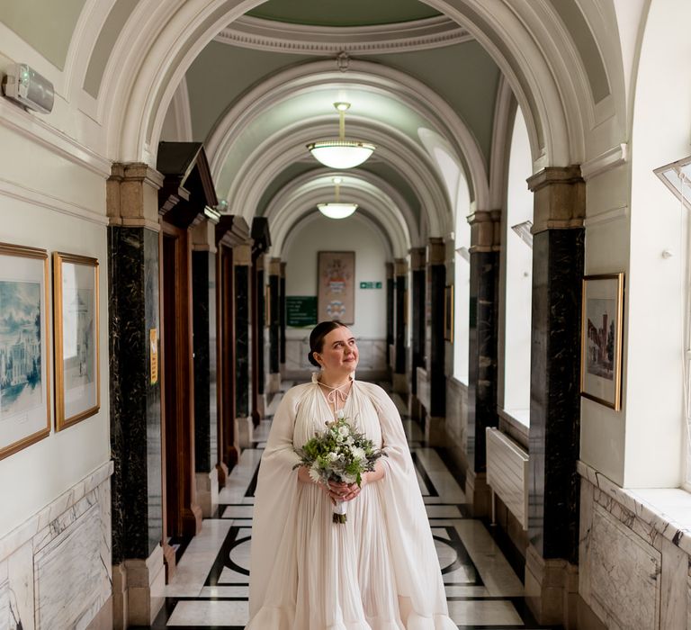 Bride in a Lanvin wedding dress with ruffle hem, bridal cape and mules