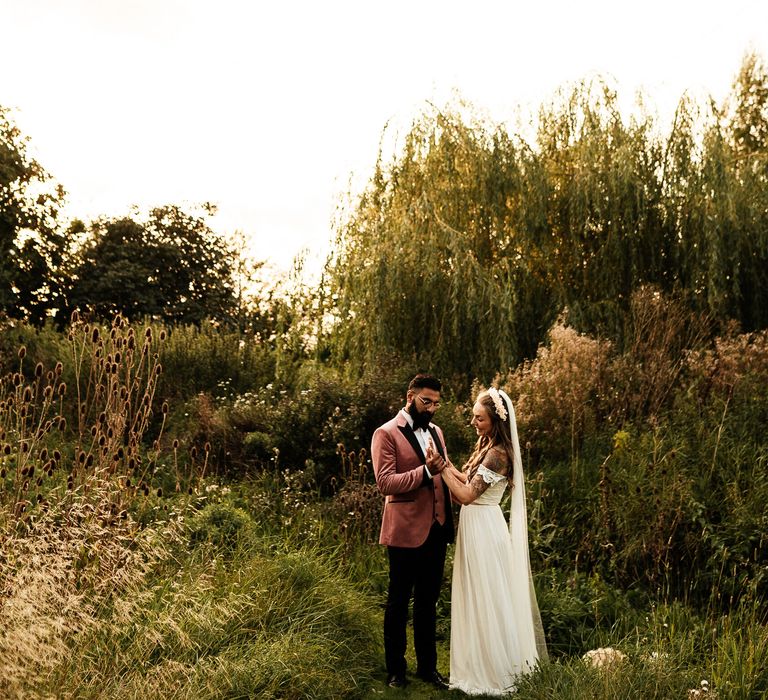 Bride & groom stand in the garden during golden hour 