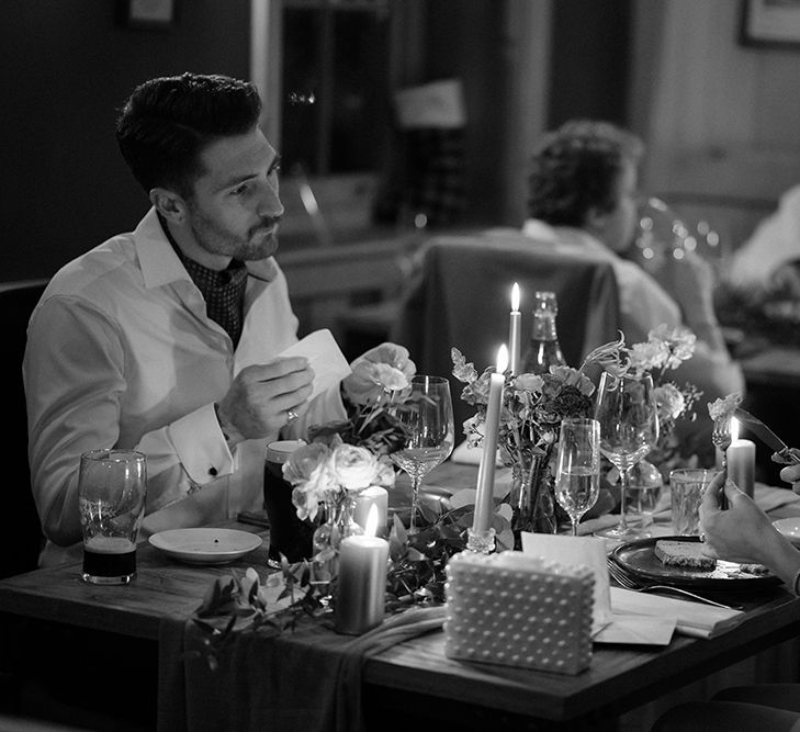 Bride & groom sit together during reception dinner in black & white image