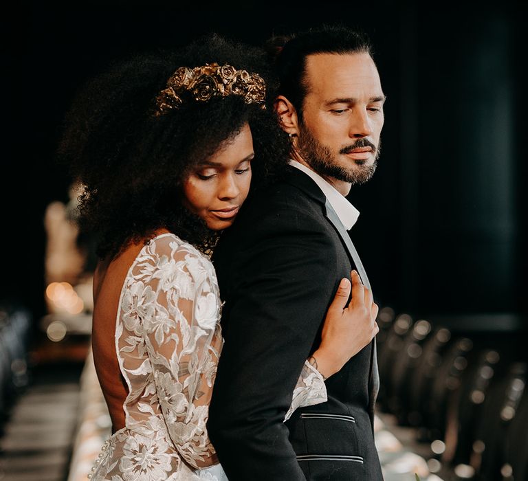 Bride embraces groom from behind whilst leaning her head on his back