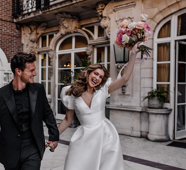 Happy bride and groom in a black suit and princess wedding dress at their intimate luxury wedding in London 