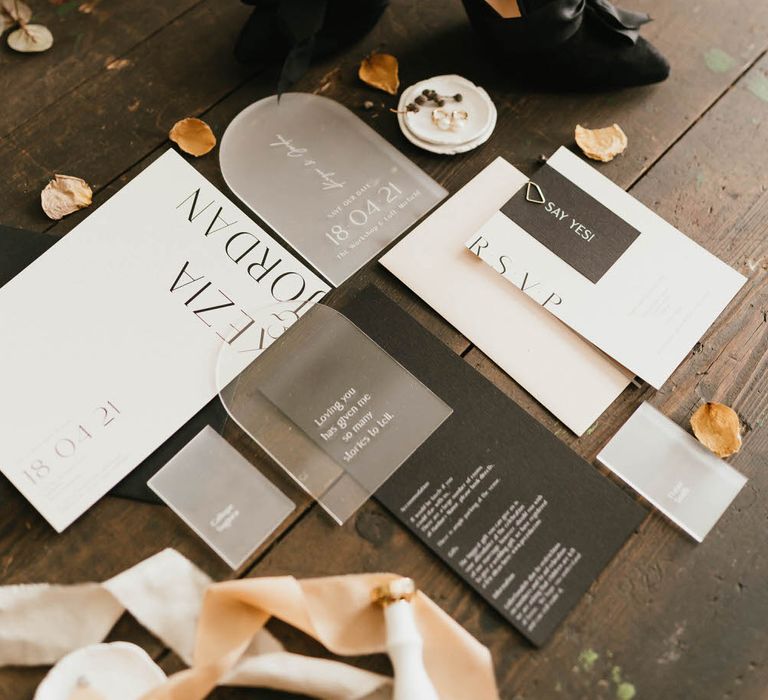 black velvet heeled mules with ribbon detail, next to minimal and sleek wedding stationery and neutral petal confetti