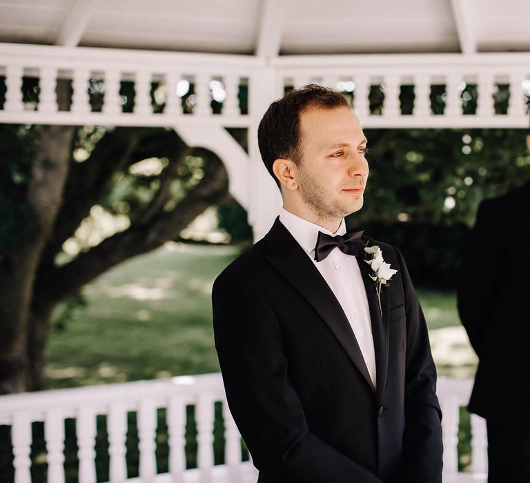 Groom in black tie and white floral boutonnière with groomsmen