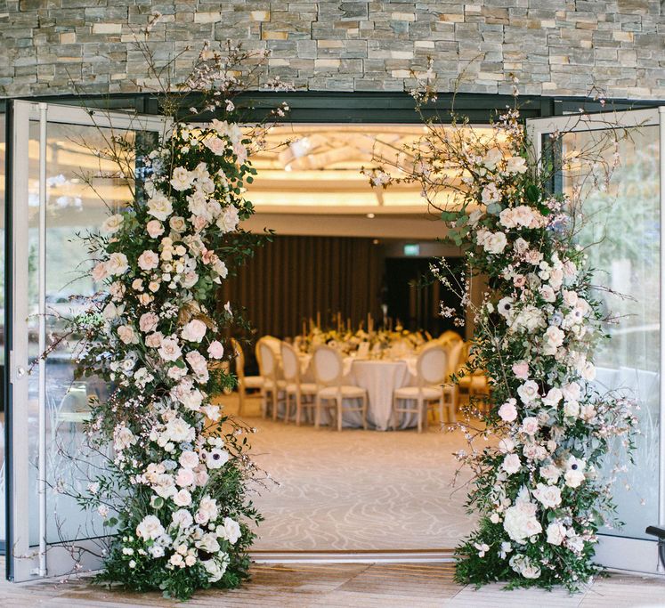 Vertical flower arrangement of hydrangea, eucalyptus, taupe roses and pretty cherry blossoms, arranged in a loose and natural style