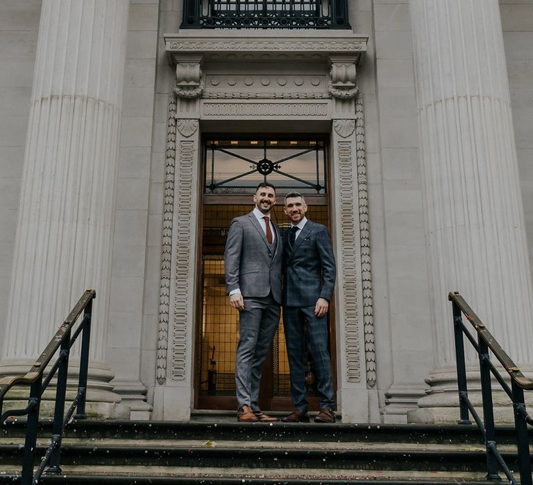 Grooms stand in front of Old Marylebone Town Hall after wedding ceremony